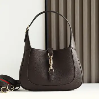 2024秋冬系列焕新演绎Gucci Jackie 1961系列肩背包 采用精细古驰安可拉红 Rosso Ancora 皮革制作 搭配全新浅金色调推入式锁扣开合 彰显品牌经典手袋的精湛工艺 新月造型和流畅廓形 这款小号肩背包搭配皮革肩带 另附红绿织带肩带 成就多样穿搭选择 型号 810232 尺寸 27.5 宽 x 19 高 x 4厘米 深 颜色 荔枝纹咖啡原厂皮 