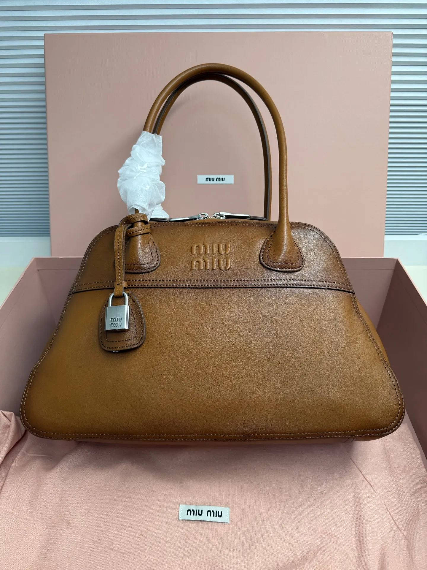 <p>Miu Miu Vivant 植鞣小羊皮 写给时间的反叛情书 中号 40cm 的容量被植鞣皮撑起饱满的弧度 它装得下职场必备 却因小羊皮的自然垂坠感而毫无 工具包 的笨重 这是给 既要效率也要美感 的知识分子的答案 </p><p> 型号 5BB196</p><p> 尺寸 40*24*13cm</p>