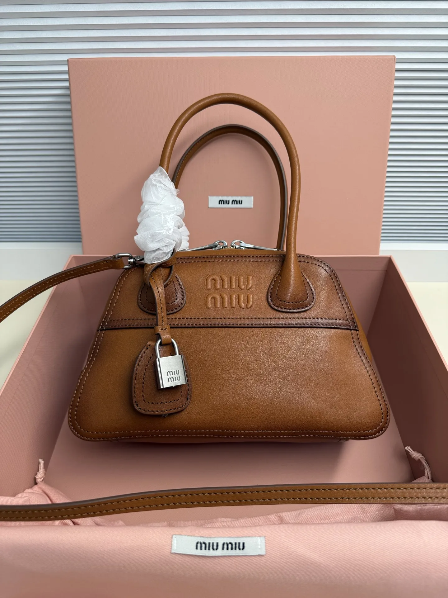 <p> Miu Miu Vivant 迷你 选用细腻绒面牛皮革 哑光质感像抚摸一片柔软的云 光线掠过时 泛起微醺般的光晕 高级感拉满 经典保龄球包型 麂皮让原本立体的线条变得柔和慵懒 自然垂坠出 不刻意 的时髦感 同色系浮雕 Logo 若隐若现 搭配做旧金属挂锁 麂皮的软糯与金属的冷冽 碰撞出独特的 甜酷 张力</p><p> 型号 5BB200</p><p> 尺寸 28*17*9.5cm</p>