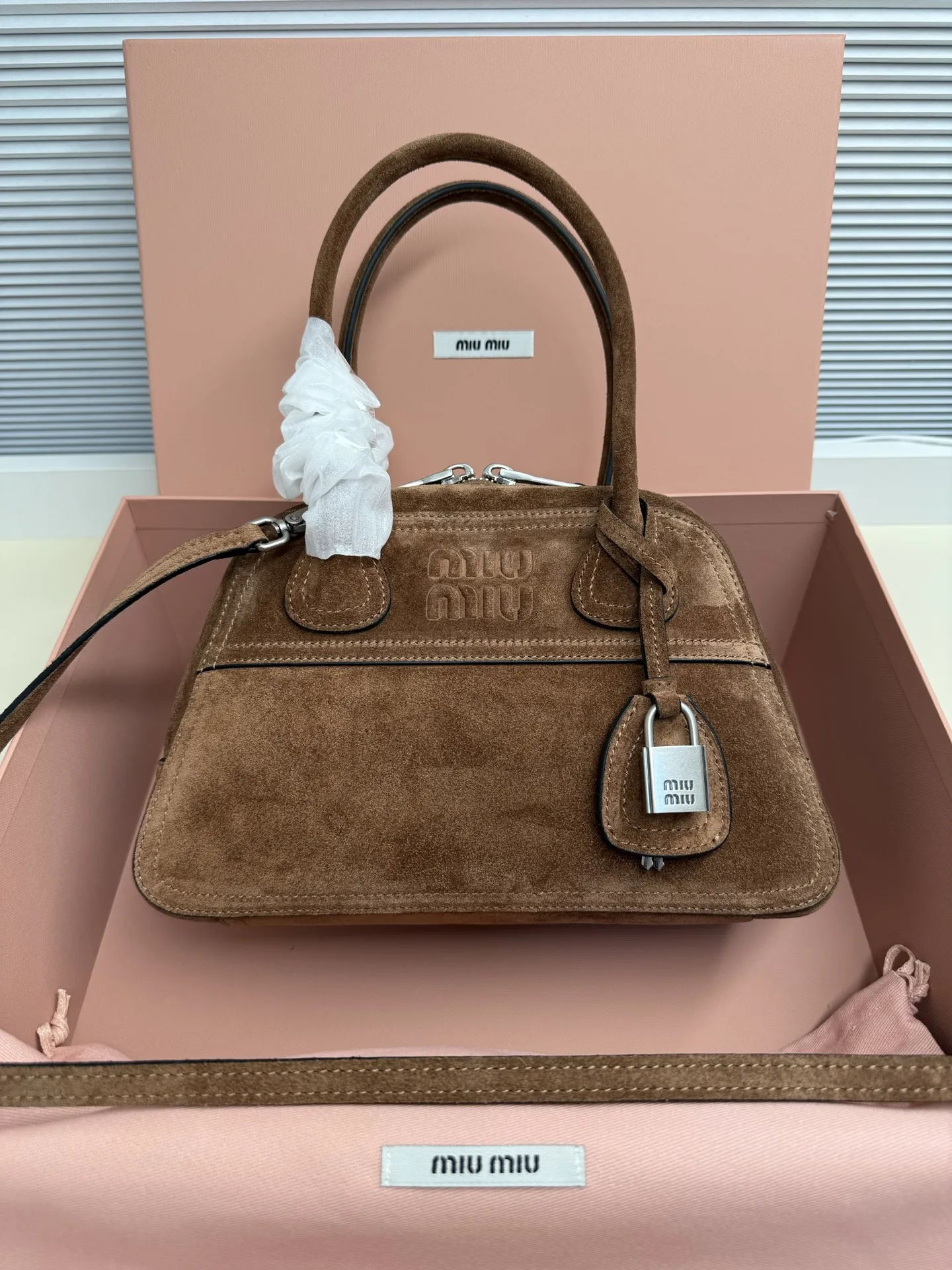 <p> Miu Miu Vivant 迷你 选用细腻绒面牛皮革 哑光质感像抚摸一片柔软的云 光线掠过时 泛起微醺般的光晕 高级感拉满 经典保龄球包型 麂皮让原本立体的线条变得柔和慵懒 自然垂坠出 不刻意 的时髦感  同色系浮雕 Logo 若隐若现 搭配做旧金属挂锁 麂皮的软糯与金属的冷冽 碰撞出独特的 甜酷 张力</p><p>    型号 5BB200</p><p>   尺寸 28*17*9.5cm</p>