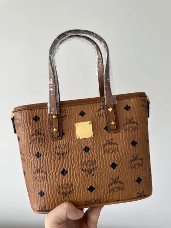 <p>MCM 原单品质 铜牌迷你购物袋 菜篮子 选用经典的印花涂层帆布精制而成 可容纳日常必需用品 附有可拆卸肩带 可单肩斜挎手提 经典百搭 实用耐看尺寸 22-17-9  款号 65002</p>