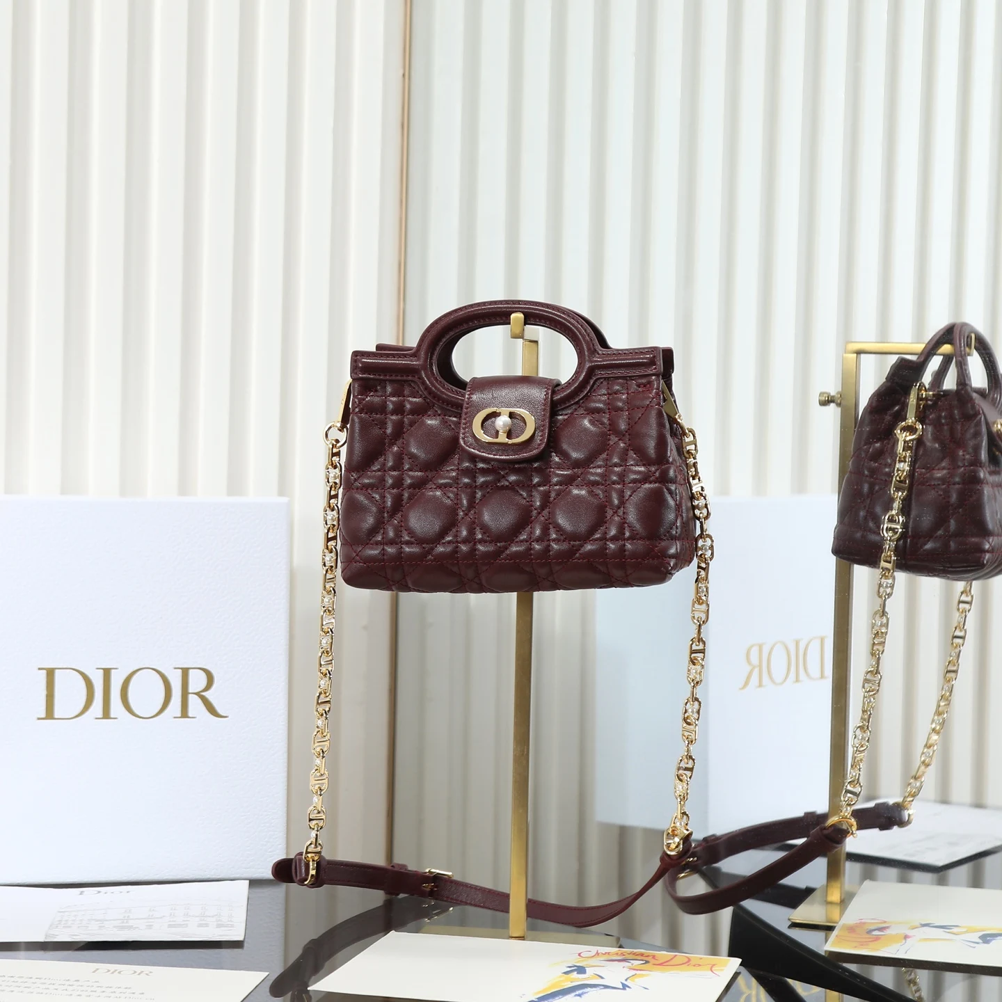 <p> 原厂级 酒红色链条手袋</p><p>这款 Dior Jolie Top Handle 迷你链条手袋是二零二六早春成衣系列新品 呈现出优雅精致的设计 采用黑色羊皮革精心制作 饰以藤格纹 翻盖点缀以金色饰面金属 CD 标志和白色树脂珠饰 内设一个隔层 可收纳各种日常用品 搭配双顶部手柄和可调节 可拆卸 CD 链条肩带 肩带由皮革带和 CD 链环组成 饰以白色树脂珠饰 可舒适手提 肩背或斜挎 可与日常或晚装造型搭配 编号: S3123</p>