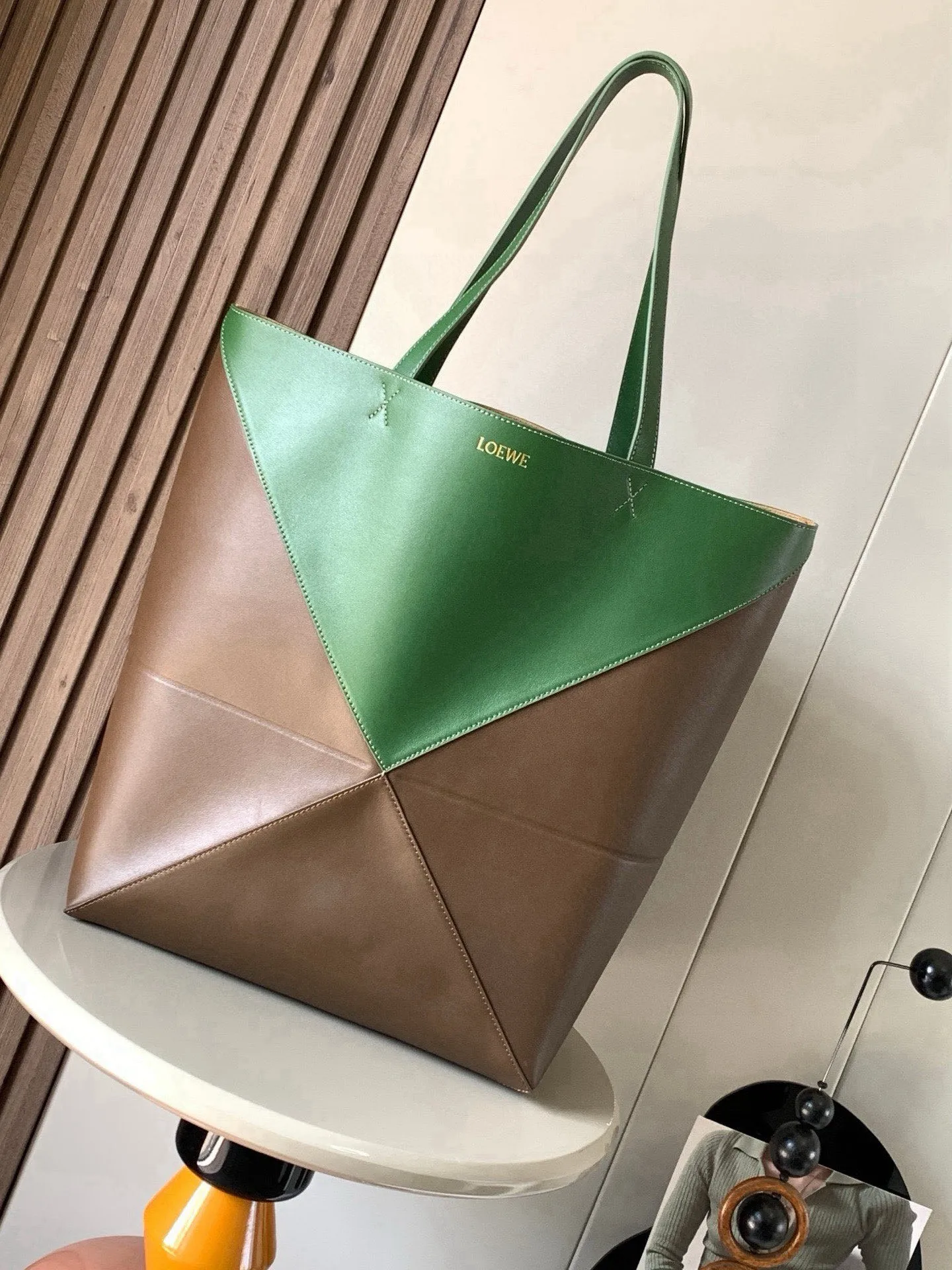 大号新款亮面牛皮革购物袋puzzle Fold手袋大号几何图形玩出花了 很久没见过这么实用又设计感满满的托特包了这款延续了Puzzle系列的几何美学以折纸包为灵感 让这只 Puzzle Fold tote 在立体和平面随意切换上身了两个尺码给大家参考哦大号容量更友好 小号很可爱 皮质都很细腻光泽本身自重超轻 能完全折叠是旅行良伴 这个大号版本采用柔软的亮面牛皮革打造尺寸 42CM 41CM 18CM款号 9033颜色 琥珀猎人绿