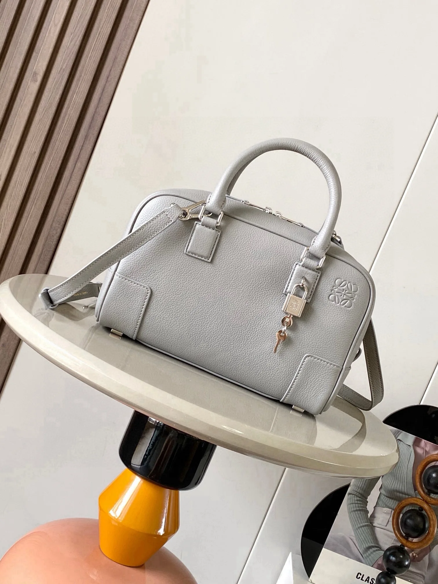 纳帕牛皮革 Amazona 23 手袋Amazona 是 LOEWE 的标志性手袋 最初于1970年代作为顶部提手软结构手袋推出 这款纳帕牛皮革版本更新了精致的比例和细节 包括一个 Anagram 雕刻挂锁 斜挎 肩背或顶部提手携带 可拆卸可调节肩带 双拉链开合 牛皮革拉链头 内部拉链隔层和按扣固定的插袋 用于存放挂锁钥匙的迷你口袋 底部保护性金属脚 可以使用肩带和个性化挂饰进行定制 金色绒面革衬里  Anagram 压纹尺寸 23cm 10cm 15cm款号 9078颜色 灰色荔