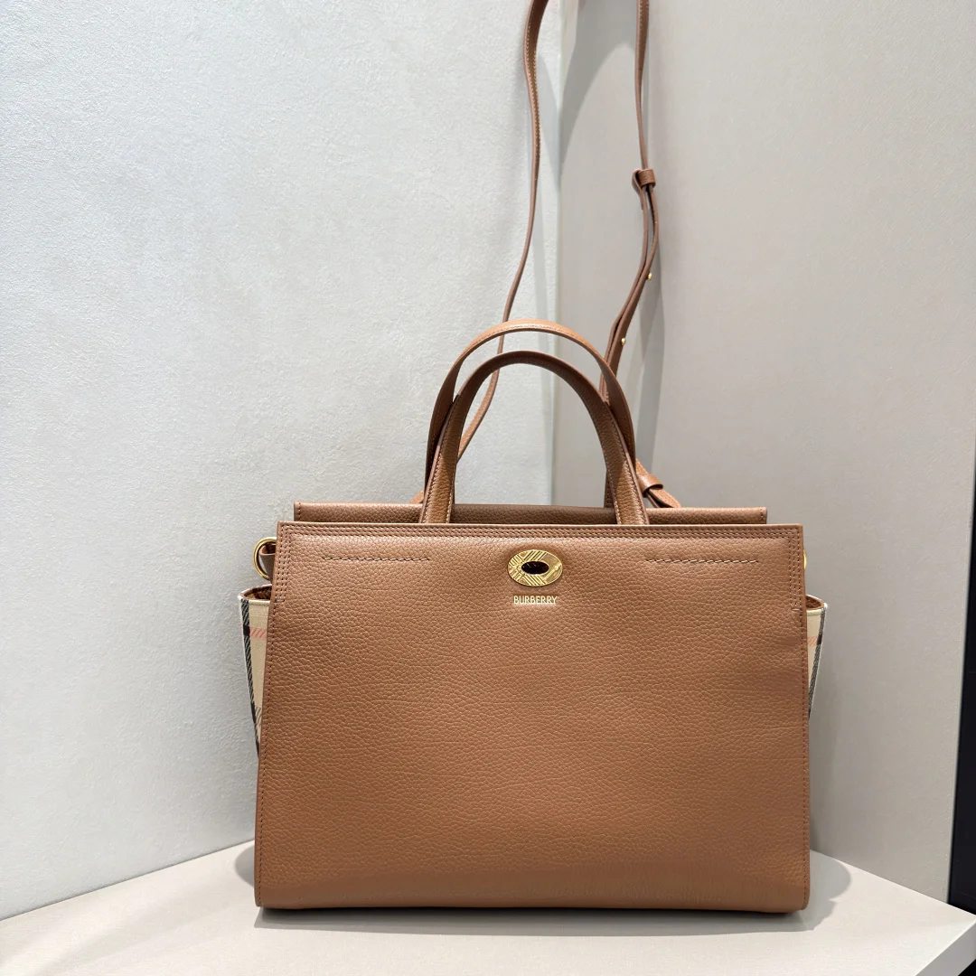 特级Cotswolds 格纹托特包 选用粒纹小牛皮材质打造 设有 Burberry 格纹侧边裁片 搭配同设计标志性沙米色内衬 精巧款式 内部空问充裕 融入格纹镌纹开合与D型环配件 灵感源自品牌标志性 Trench 风衣腰带 可手拿携带 或使用肩背带缔造肩背造型 尺寸30.5 × 13 × 22.5cm 型号0611