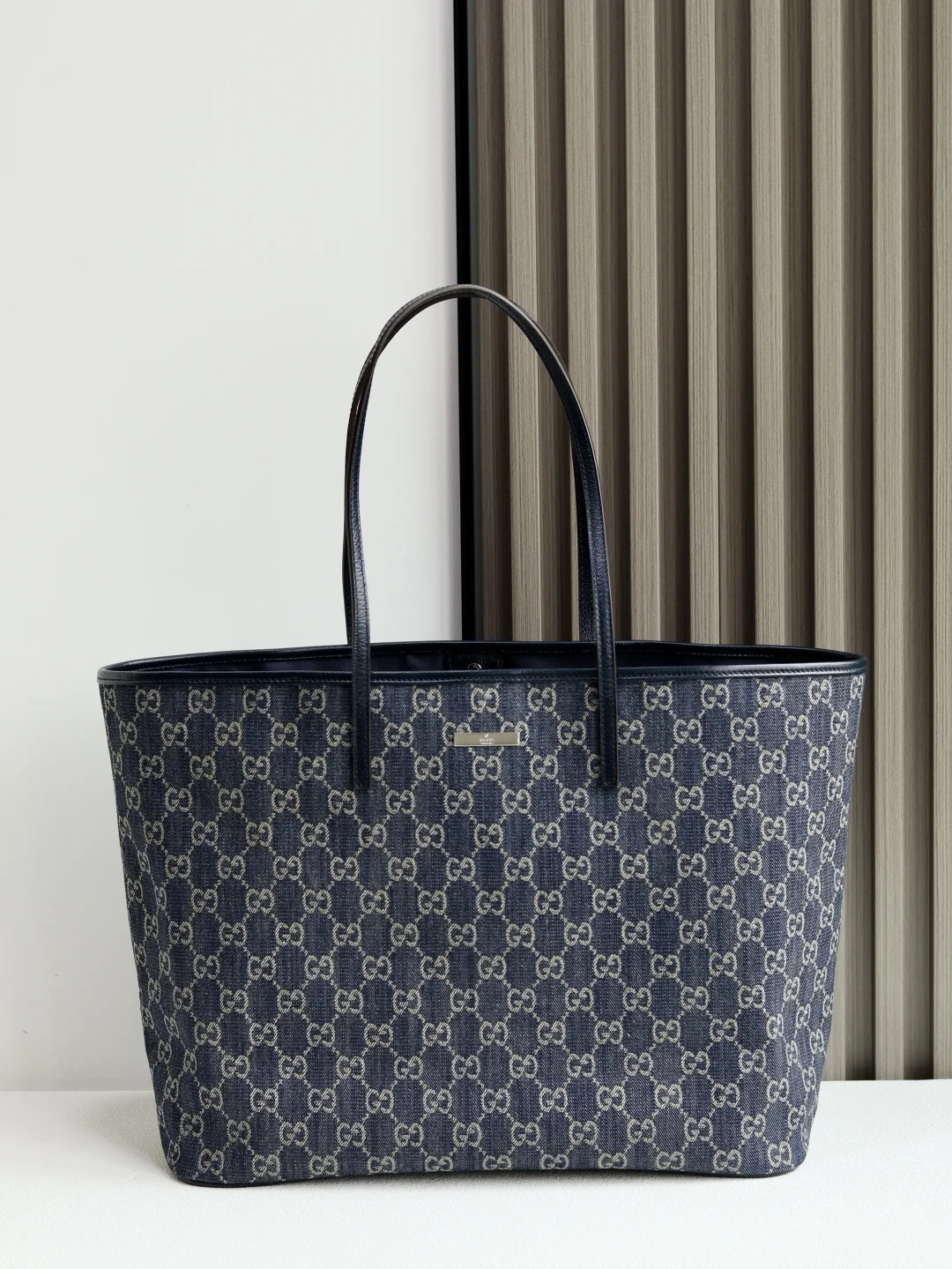 Generation Gucci系列深入探索品牌的典藏素将不同世代的设计融入一个美学叙事中 GG牛仔布搭配品牌标识徽牌 为精致廓形增添标志性细节 这款托特包提升了日常风格 内部配有拉链口袋 深蓝色水洗GG牛仔布深蓝色皮革滚边钯色金属配件Gucci牌匾蓝色尼龙衬里内部 1个口袋皮革肩带下垂 25.5厘米饰按扣闭合型号 874745 尺寸 38厘米 宽 x 29.5厘米 高 x 13厘米 深 颜色 蓝色/牛仔 意大利创作