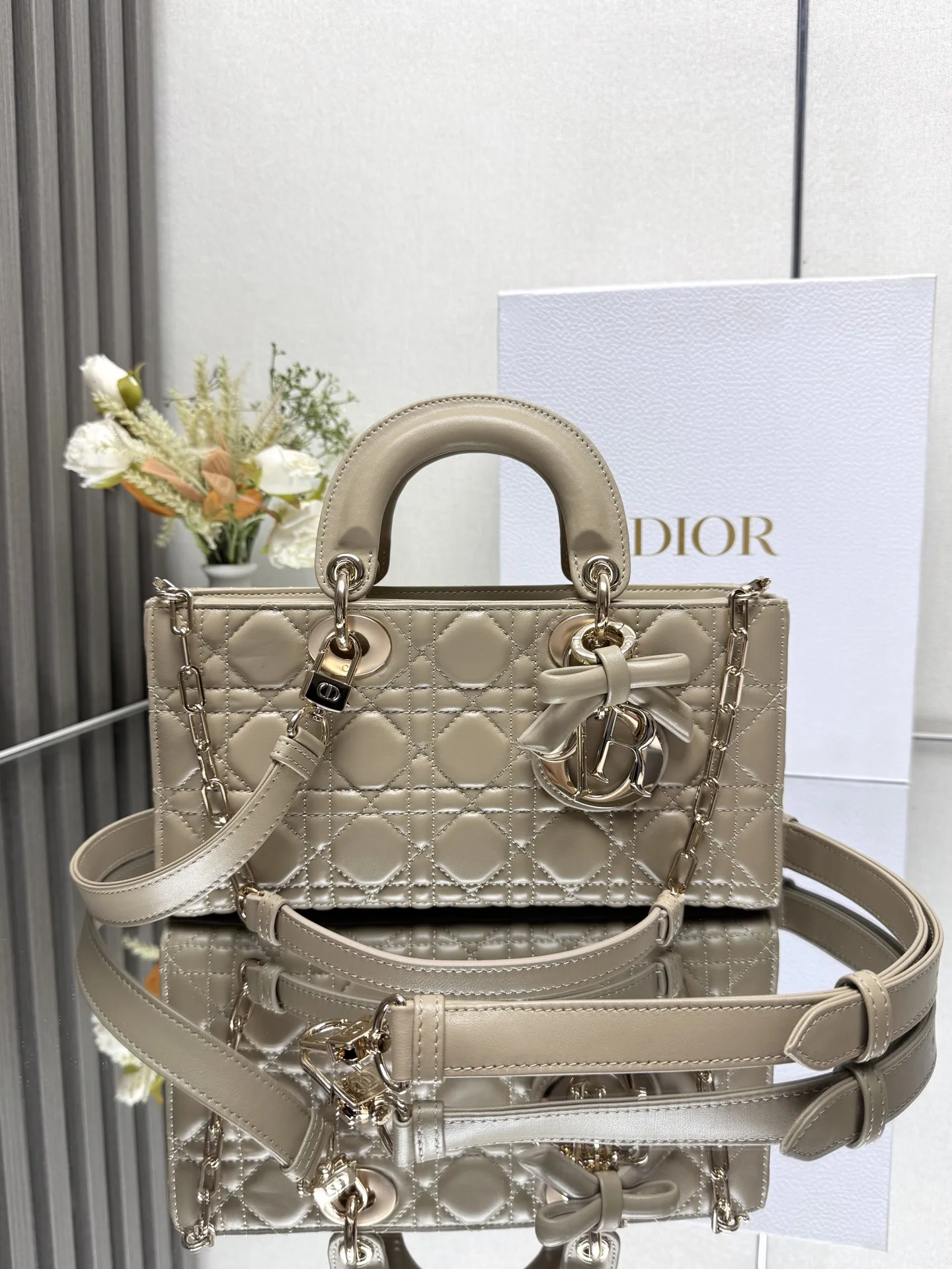 中号 LADY D-JOY 手袋 杏色带蝴蝶结小羊皮 这款 Lady D-Joy 手袋凸显 Lady Dior 系列的简约美学 集中体现了 Dior 对典雅和美丽的深刻洞见 采用黑色哑光牛皮革精心制作 以经典的藤格纹缉面线打造醒目的绗缝细节 精良的缝制工艺显露无遗 同色调金属 D.I.O.R. 吊饰彰显优雅气质 小号款式 搭配可拆卸的链条肩带和可调节 可拆卸的皮革肩带 可手提 肩背或斜挎 是日常造型的理想之选 可拆卸链条肩带可拆卸 可调节的皮革肩带型号 0540尺寸 26×13.5×5 cm可收纳一部 iPhone和其他配饰238620