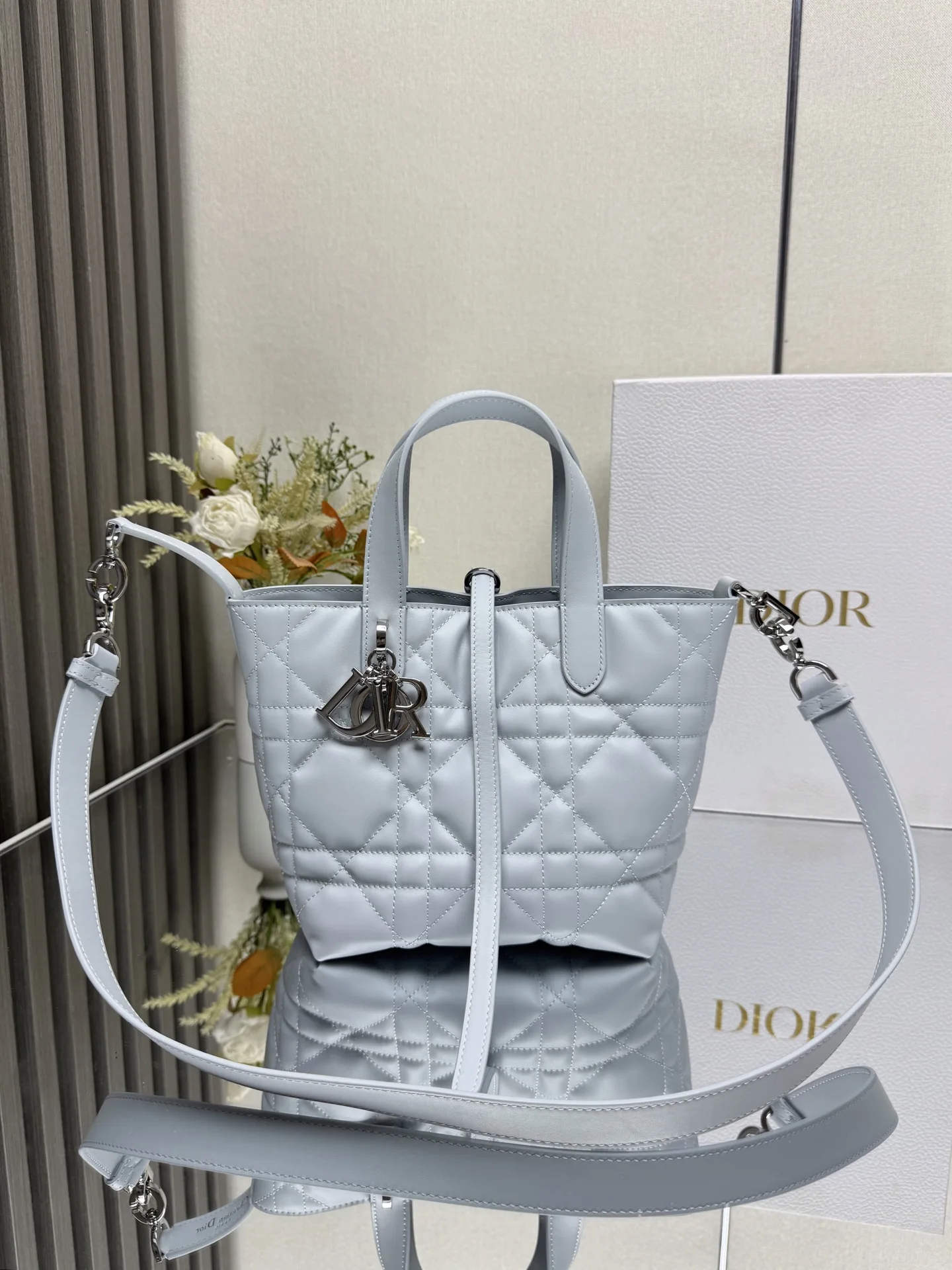 这款 Dior Toujours竖版手袋是二零二五早春成衣系列新品 时尚实用 别具一格 采用冰川蓝色牛皮革精心制作 饰以超大藤格纹缉面线 宽敞的内部隔层可收纳各种日常用品 设有纤细皮革系带开合 可安全收纳各种物品 另有CD Lock 字母D旋钮式扣环 可调节两侧 提升格调 小号款式 顶部皮革手柄搭配可拆卸的皮革肩带 可手提 肩背或斜挎主体:牛皮革里料:牛皮革尺寸 16×18×12cm 款号 2835 000670