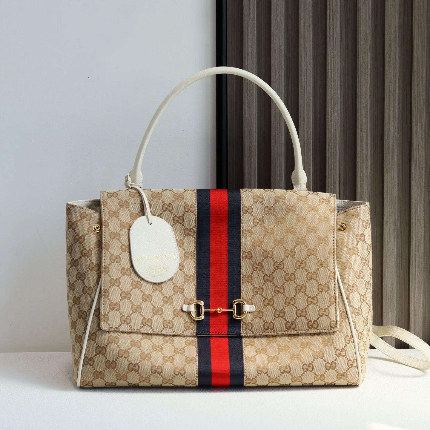 Generation Gucci系列深入探索品牌的典藏元素 将不同年代的设计融合成一种美学叙事 这款款式以手提包设计向品牌标志性的Horsebit和Web致敬 采用标志性GG帆布精制而成 沙色和白色GG帆布白色皮革滚边金色调配件沙色帆布衬里 饰菱形格纹图案Horsebit 网状结构和皮革标牌 带有 Made in Italy Gucci 标志内部 1个拉链口袋手挽垂直长度 18 - 24.5厘米可拆卸和可调节皮革肩带长度 51 - 55cm按扣磁扣开合款号 875019尺寸 37厘米 宽 x 29厘米 高 x 13厘米 深 重量 约825克颜色 杏布/白色