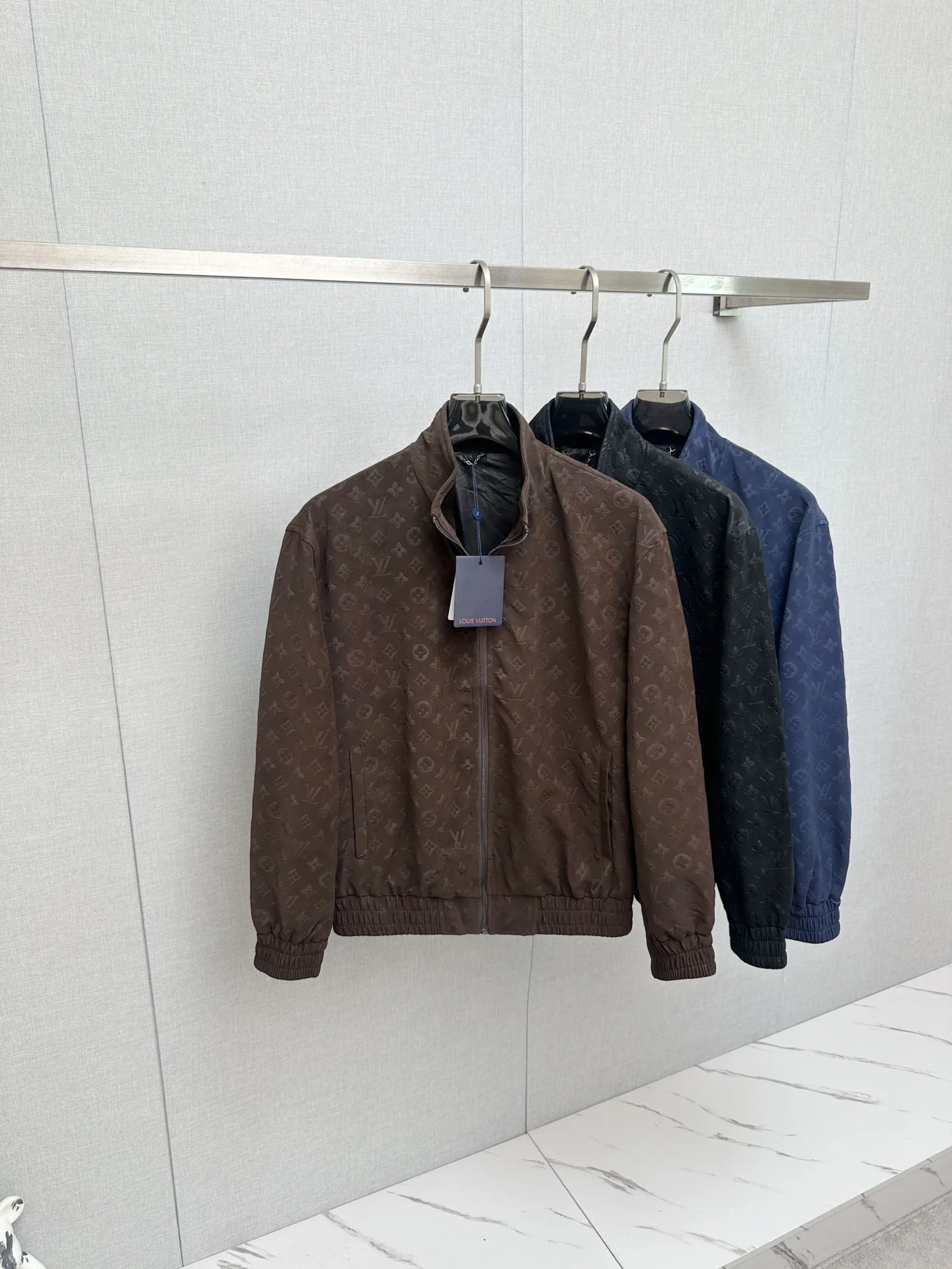 原单外套男装|高仿外套男装|精仿外套男装|一比一外套男装1V/路易 FW26 Monogram老花满印麂皮压花立领夹克外套面料采用定制麂皮质感面料 哑光高级雾面色泽 通体满幅LV老花立体压花 独立模具压制 花纹深浅 间距 排布严格对标原版 压印力度把控到位 不会出现压纹过浅模糊 压穿面料的问题 从面料染色 压花工艺 车位缝制到辅料定制 全程对标原版工序 统一对色校准色调 Size S-2XL