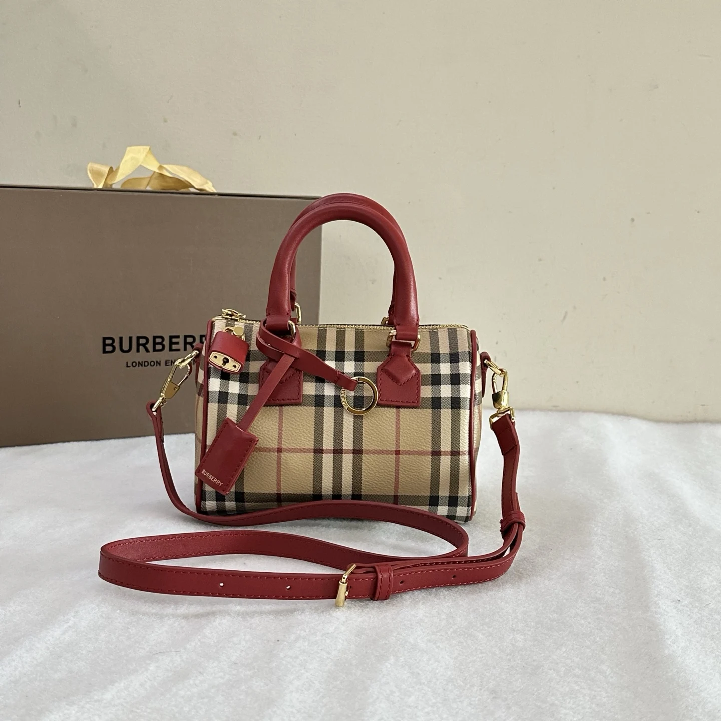B家枕头包 立挺设计 装饰 Bur 格纹 搭配皮革裹覆挂锁和行李吊牌 18.5 x 11 x 12cm.顶部皮革提柄.可拆可调式肩背带.拉链开合 手绘涂漆边缘.光泽金属配件.皮革裹覆挂锁.行李吊牌.行李吊牌饰有 Bur 字母压花徽标