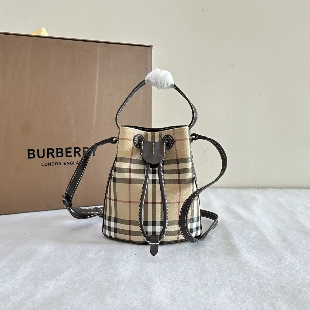 B包迷你格纹水桶包 选用涂层棉质混纺面料打造 于意大利工坊精制而成 装饰 Burberry 格纹印花 包型柔软立挺 内衬为棉质面料 搭配抽绳开合 融入皮革盾牌栓扣设计 可使用顶部提柄手拎 或以可拆式肩背带缔造斜背造型 顶部皮革提柄.可拆可调式皮革斜背带.抽绳开合.手绘涂漆边缘. 光泽金属配件.棉质内衬.尺寸16.5 x 11 x 18.5cm